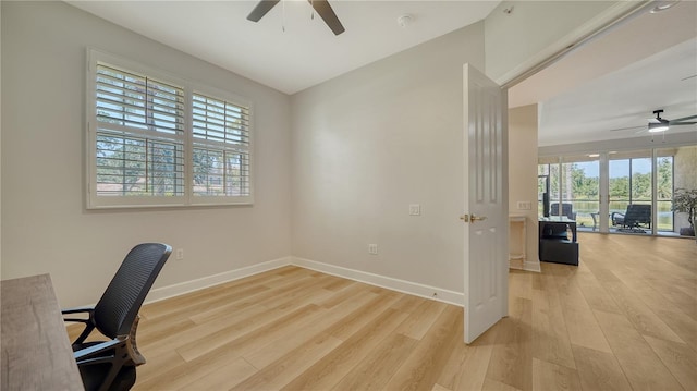 unfurnished office featuring baseboards, a ceiling fan, and light wood finished floors