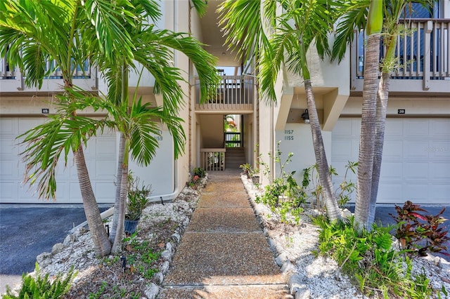property entrance featuring stucco siding, a garage, and a balcony