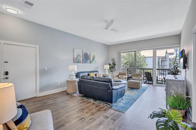 living room featuring baseboards, ceiling fan, visible vents, and wood finished floors