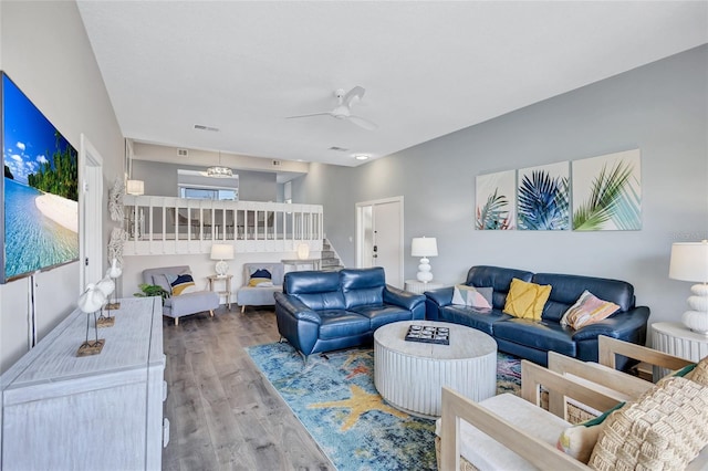 living area with stairway, visible vents, ceiling fan, and wood finished floors