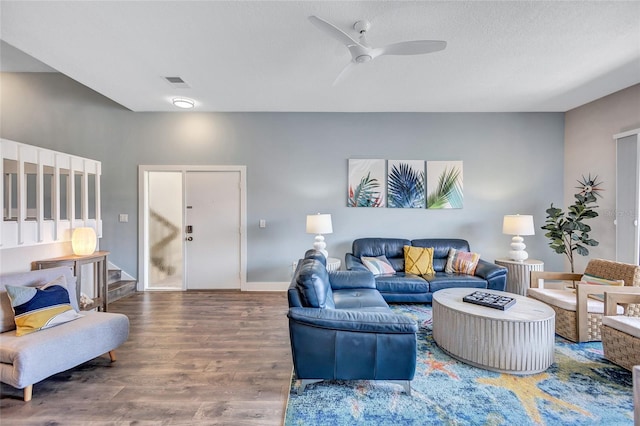 living room featuring visible vents, wood finished floors, ceiling fan, and stairs