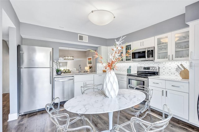 kitchen with a sink, stainless steel appliances, visible vents, glass insert cabinets, and white cabinets