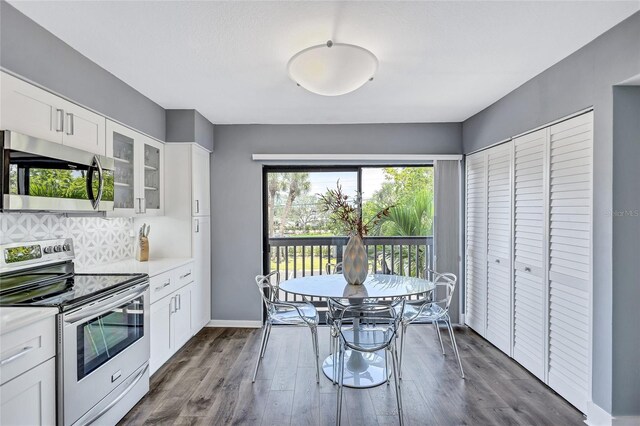 kitchen featuring white cabinetry, light countertops, appliances with stainless steel finishes, and glass insert cabinets