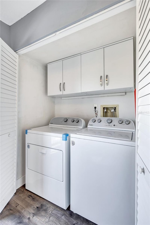 laundry room featuring dark wood-style flooring, washing machine and dryer, and cabinet space