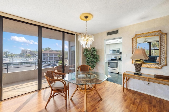6415 Midnight Pass Rd Unit 204, Sarasota, FL 34242 - dining space featuring wood finished floors, a chandelier, and a textured ceiling