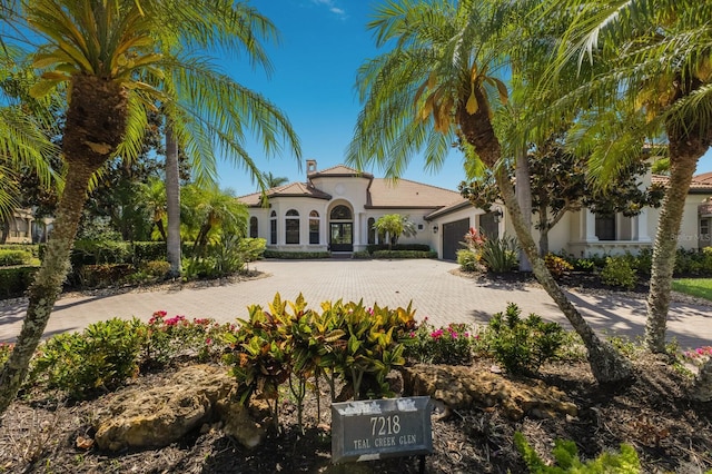 mediterranean / spanish-style house featuring a garage, stucco siding, and decorative driveway