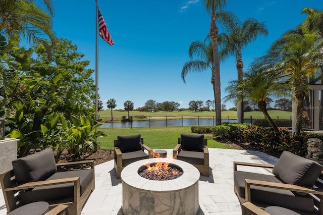 view of patio featuring an outdoor fire pit, a water view, and fence