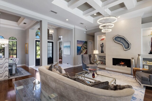 living room featuring wood finished floors, coffered ceiling, visible vents, a chandelier, and ornamental molding