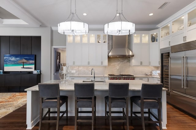 kitchen with wall chimney exhaust hood, pendant lighting, dark wood-type flooring, appliances with stainless steel finishes, and decorative backsplash