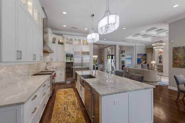 kitchen with a sink, recessed lighting, premium appliances, an inviting chandelier, and coffered ceiling