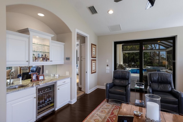 bar with a sink, wine cooler, dark wood-type flooring, visible vents, and vaulted ceiling