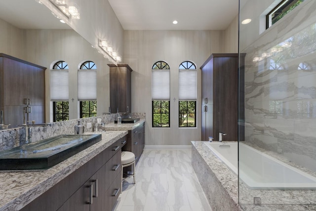 bathroom featuring a tub, plenty of natural light, marble finish floor, and vanity