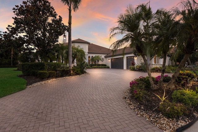 view of front of property with stucco siding, an attached garage, and decorative driveway