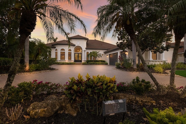mediterranean / spanish-style home featuring french doors, decorative driveway, stucco siding, and a garage
