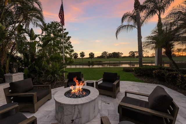 view of patio / terrace with an outdoor living space with a fire pit, fence, and a water view