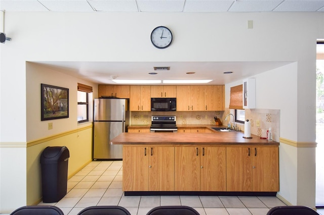 625 30th Ave W Unit G210, Bradenton, FL 34205 - kitchen featuring stainless steel appliances, a peninsula, light tile patterned floors, tasteful backsplash, and healthy amount of natural light