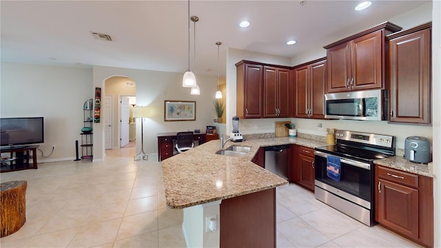 116 Navigation Cir Unit 106, Osprey, FL 34229 - kitchen with appliances with stainless steel finishes, a peninsula, arched walkways, a sink, and light stone counters