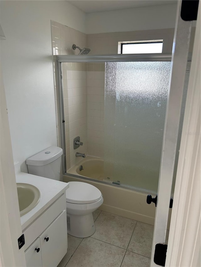 bathroom featuring vanity, enclosed tub / shower combo, tile patterned floors, and toilet