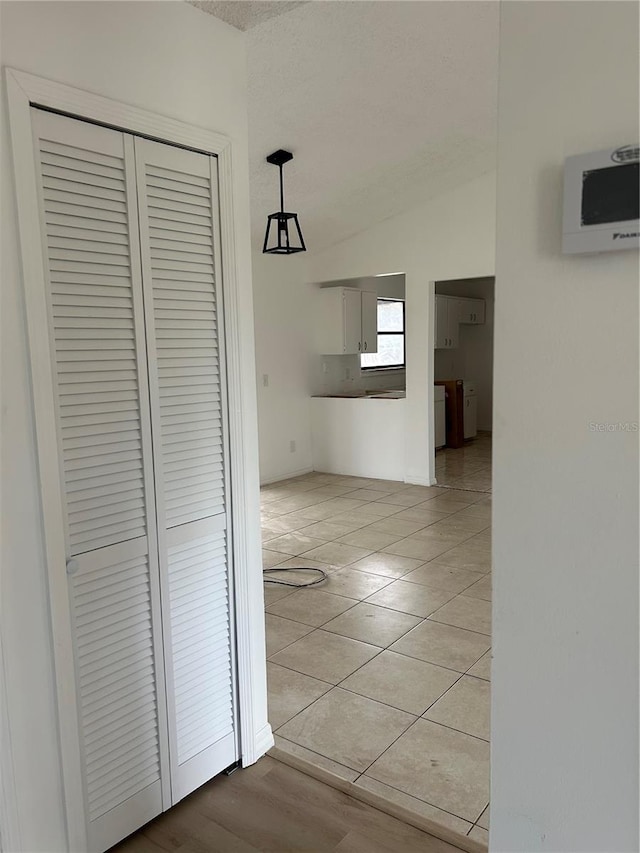 hallway featuring light tile patterned floors and vaulted ceiling