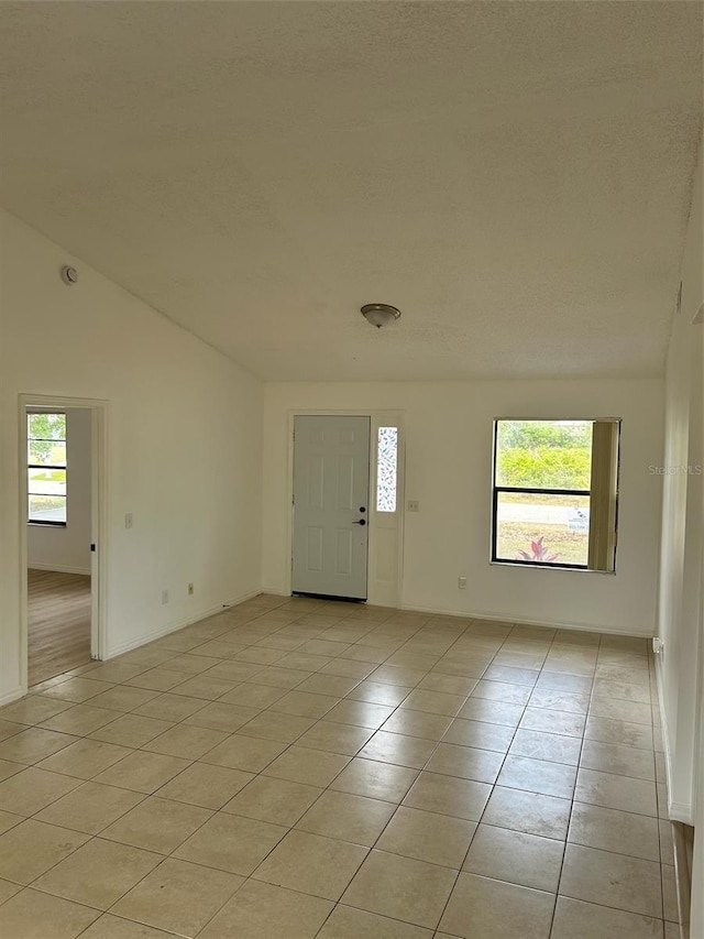 foyer entrance with baseboards, a textured ceiling, and light tile patterned floors