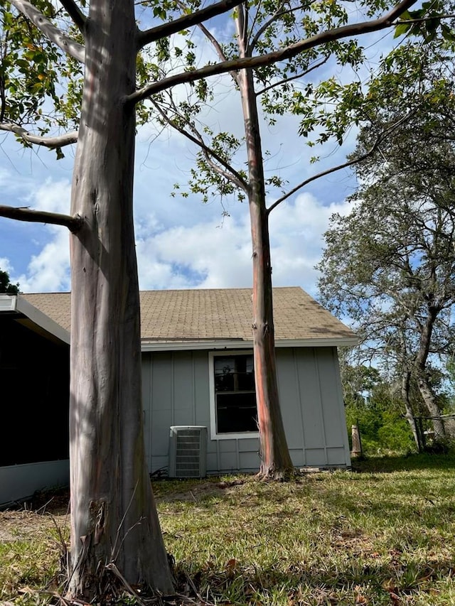 view of side of property featuring central AC unit, board and batten siding, and roof with shingles