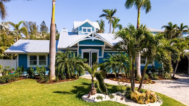 view of front of home featuring metal roof, driveway, and a front lawn