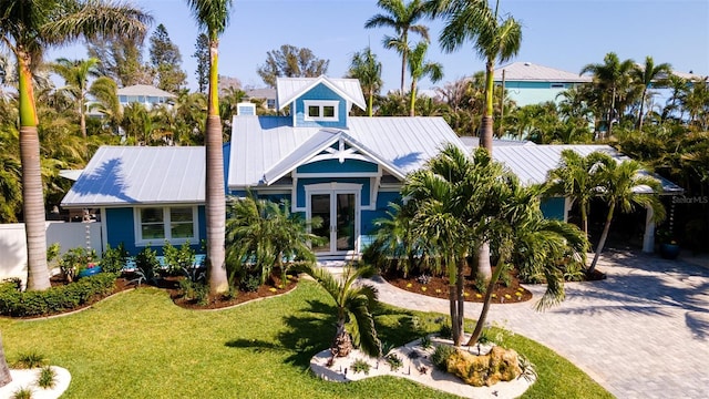view of front of property with french doors, decorative driveway, metal roof, and a front lawn