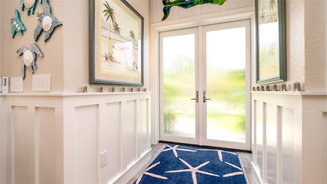 entryway with french doors, a wainscoted wall, and a decorative wall
