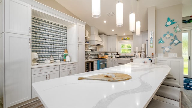 kitchen featuring decorative backsplash, wine cooler, custom exhaust hood, a breakfast bar, and white cabinetry