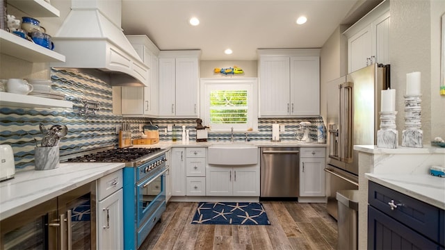 kitchen with white cabinets, high quality appliances, a sink, and backsplash