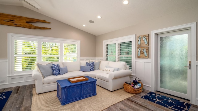 living area with plenty of natural light, wood finished floors, lofted ceiling, and a wainscoted wall