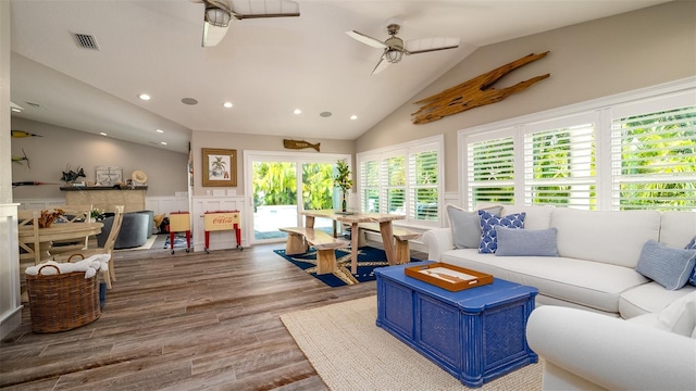 living area featuring visible vents, wood finished floors, lofted ceiling, ceiling fan, and a wainscoted wall