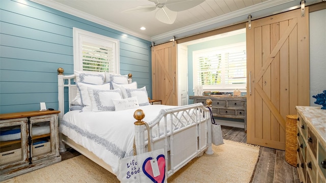 bedroom with crown molding, a barn door, ceiling fan, and wood finished floors