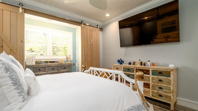 bedroom with crown molding, a barn door, and baseboards