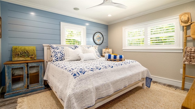 bedroom with baseboards, ornamental molding, multiple windows, and wood finished floors