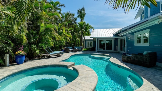 view of swimming pool with an outdoor living space, a pool with connected hot tub, french doors, and a patio