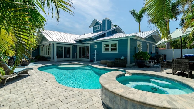 view of swimming pool featuring fence, a pool with connected hot tub, and a patio area