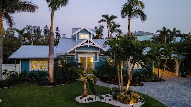 view of front of house with metal roof, driveway, and a front lawn