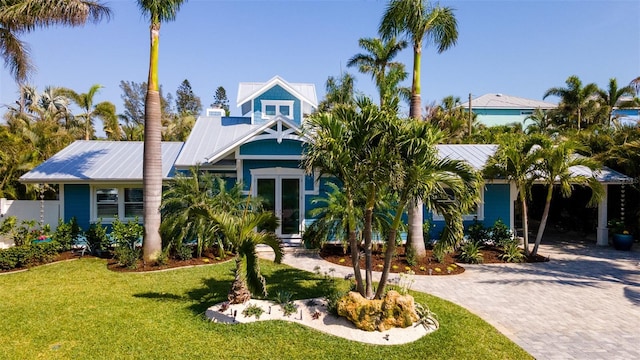 view of front of house featuring decorative driveway, metal roof, and a front lawn