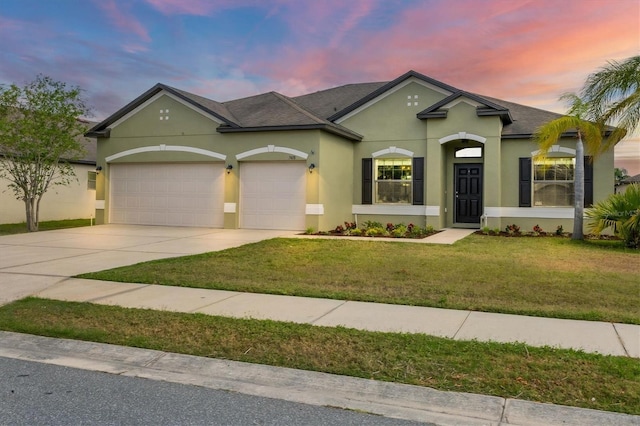 7418 61st St E, Palmetto, FL 34221 - view of front of home with roof with shingles, an attached garage, stucco siding, a lawn, and driveway