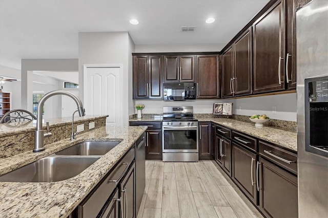 7418 61st St E, Palmetto, FL 34221 - kitchen with light stone countertops, a sink, light wood finished floors, stainless steel appliances, and visible vents