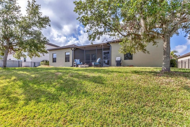 7418 61st St E, Palmetto, FL 34221 - rear view of house with a yard, fence, a sunroom, and stucco siding