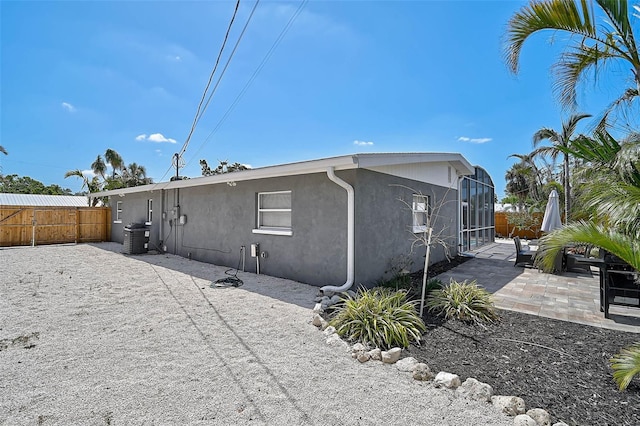 1112 65th St NW, Bradenton, FL 34209 - back of house featuring fence, stucco siding, a patio area, glass enclosure, and central air condition unit