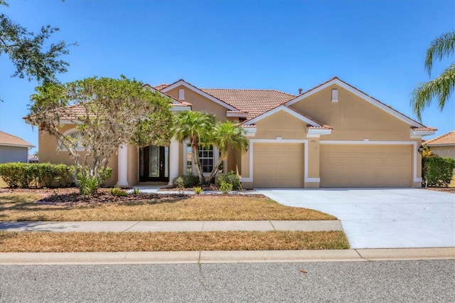 view of front of property with an attached garage, a tiled roof, stucco siding, and driveway