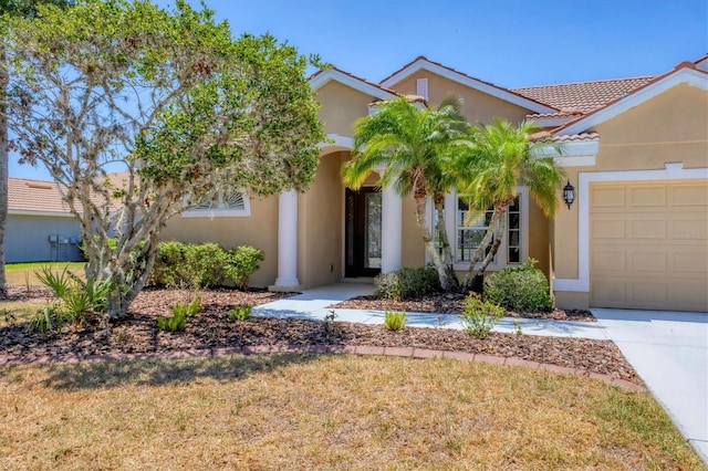 view of front of house featuring a garage, stucco siding, a tile roof, concrete driveway, and a front yard