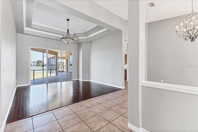 unfurnished room with crown molding, visible vents, tile patterned flooring, a raised ceiling, and a chandelier