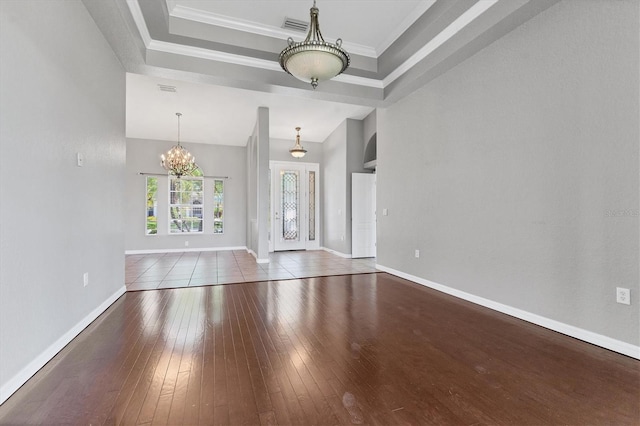 interior space with an inviting chandelier, baseboards, a raised ceiling, and wood-type flooring