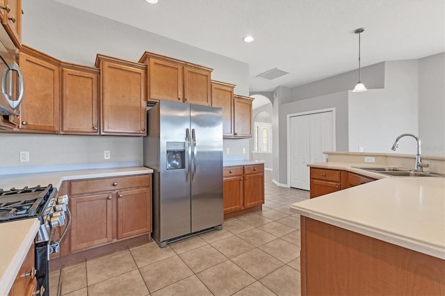 kitchen with arched walkways, light countertops, stainless steel appliances, and a sink