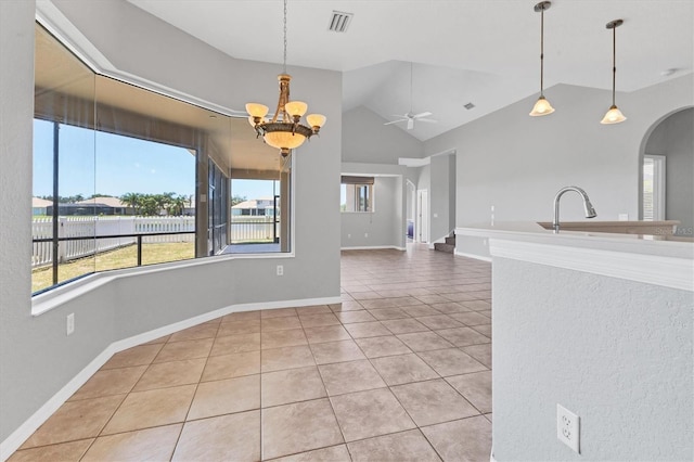 unfurnished dining area featuring visible vents, ceiling fan with notable chandelier, tile patterned flooring, vaulted ceiling, and arched walkways