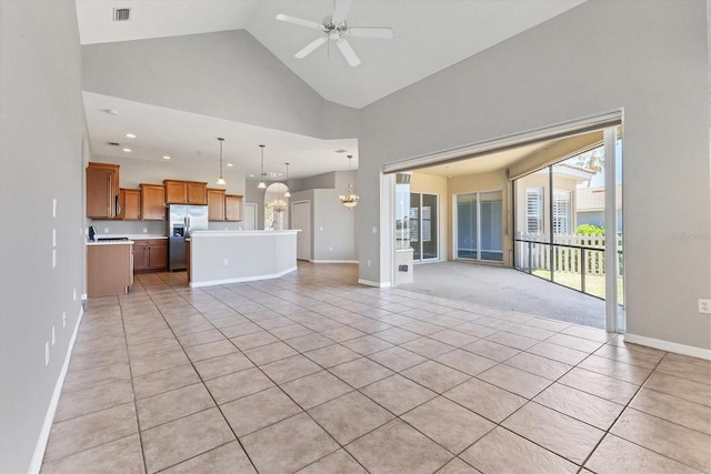 unfurnished living room with ceiling fan with notable chandelier, high vaulted ceiling, visible vents, baseboards, and light tile patterned flooring